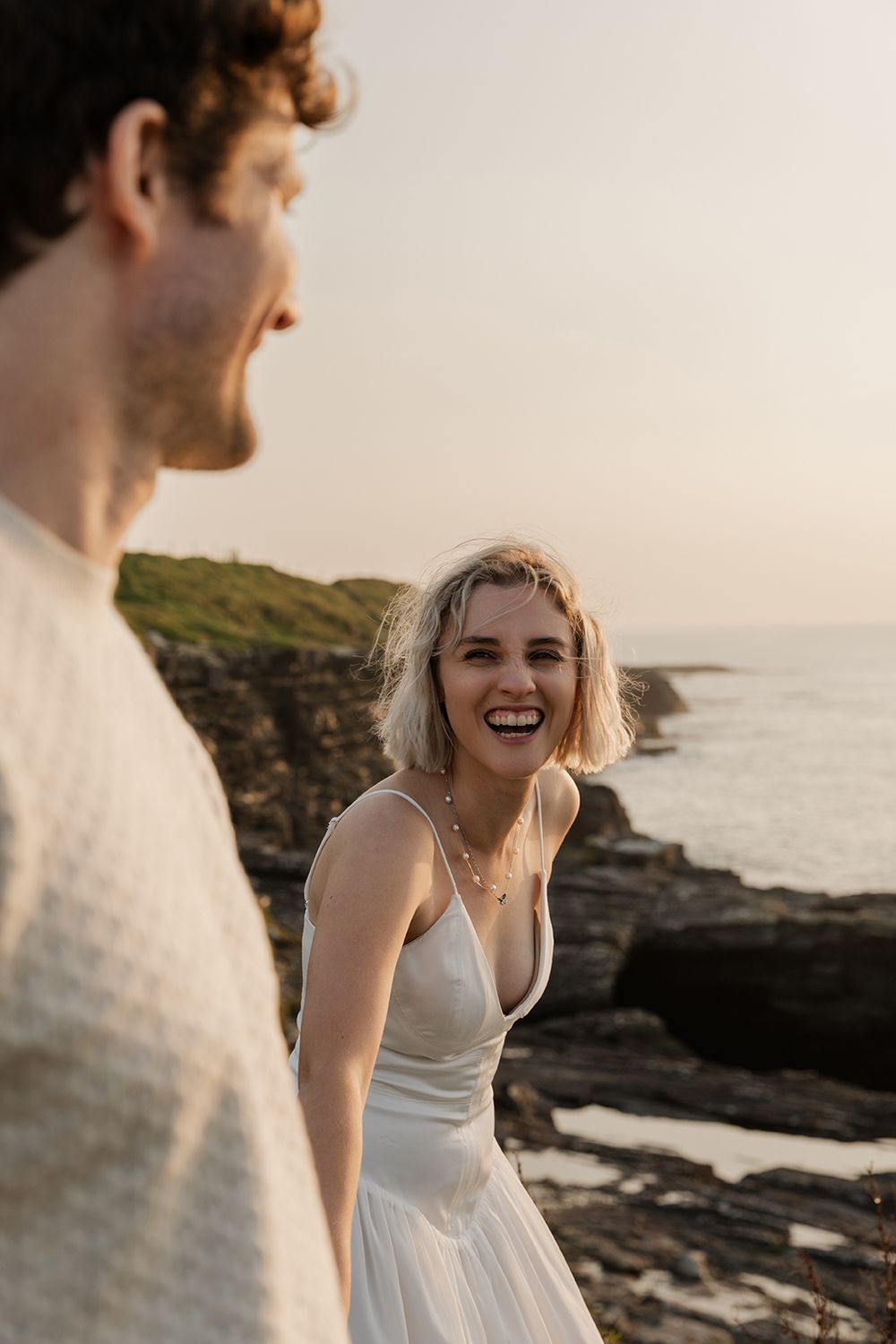 adventure photo session on the cliff walk from Doolin to Cliffs of Moher, women is looking at her partner and laughing