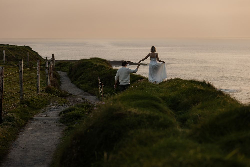 couple is holding hands and walking on the cliff walk from Doolin to cliffs of Moher