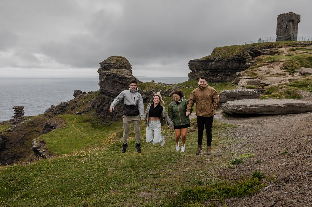 family holding hands and jumping at the Hag's head during their adventure trip to Ireland