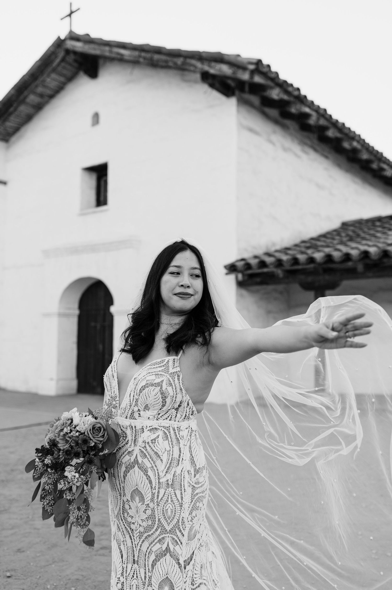 A joyful pose in a wedding dress outside a historic Spanish mission church.