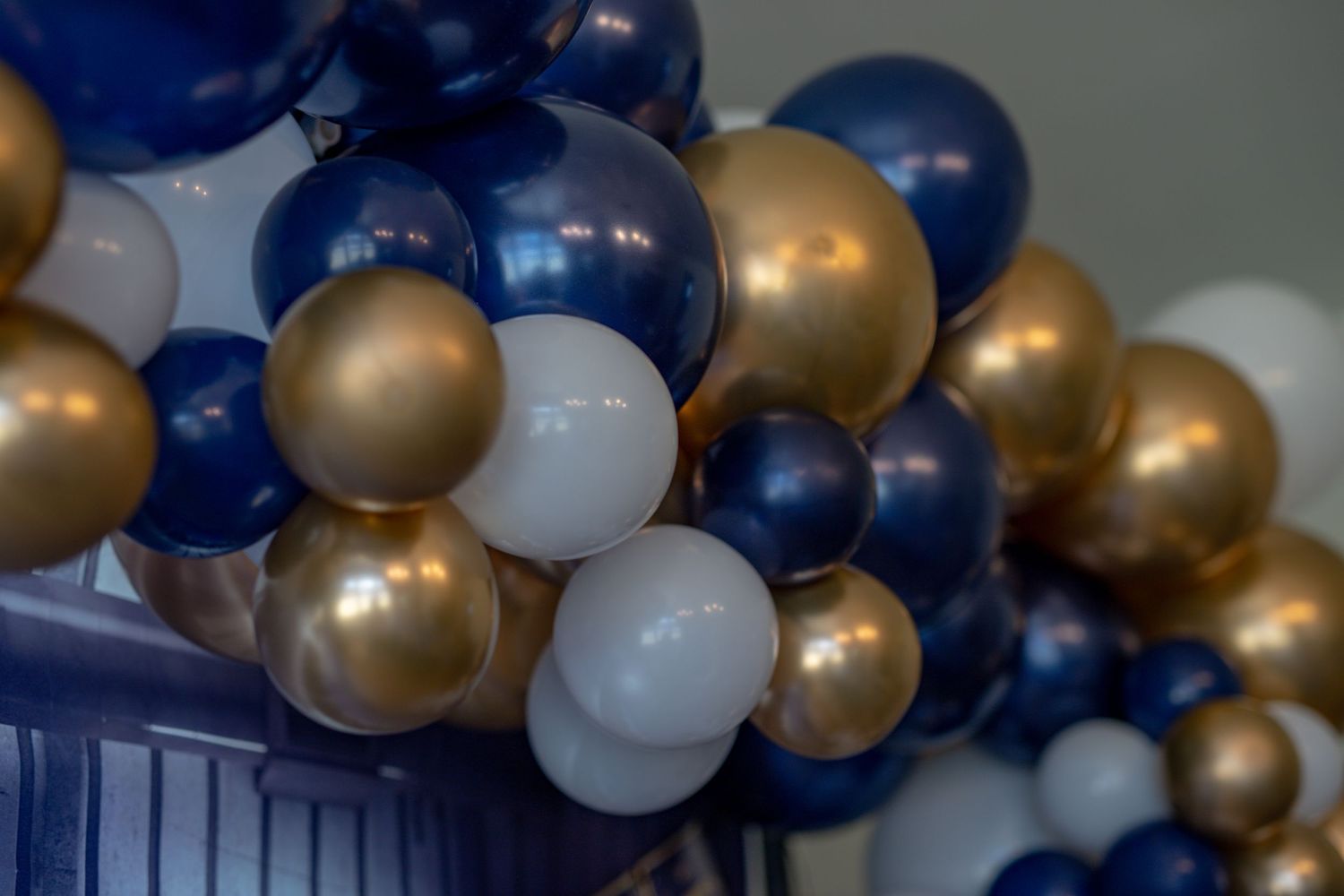 Close-up of elegant balloon garland in navy blue, gold and white colors.
