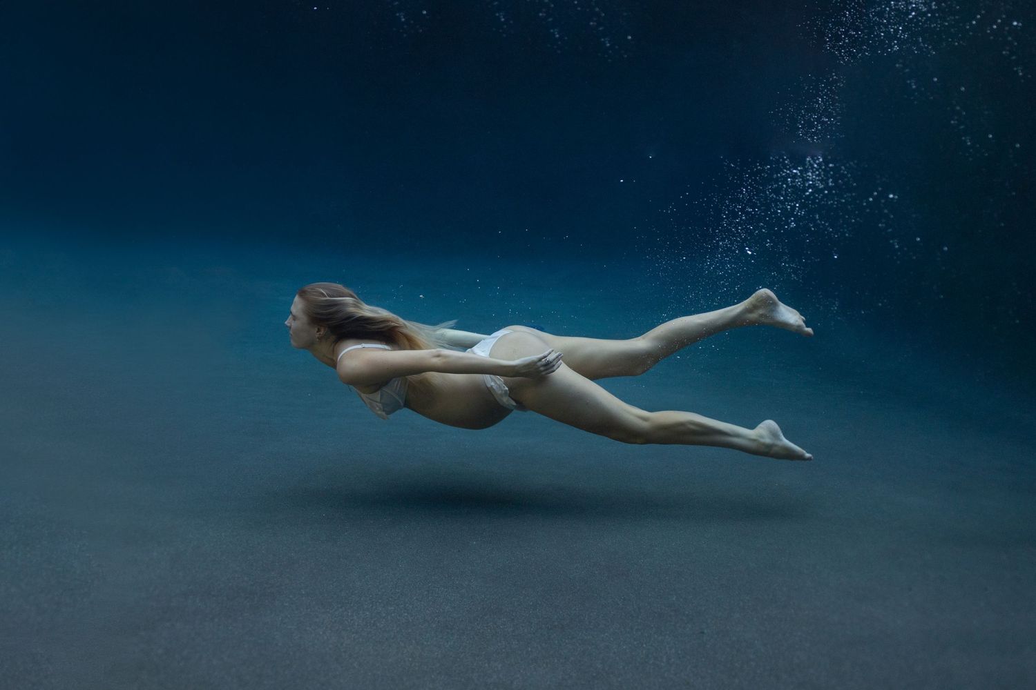 Pregnant woman swimming underwater on Maui