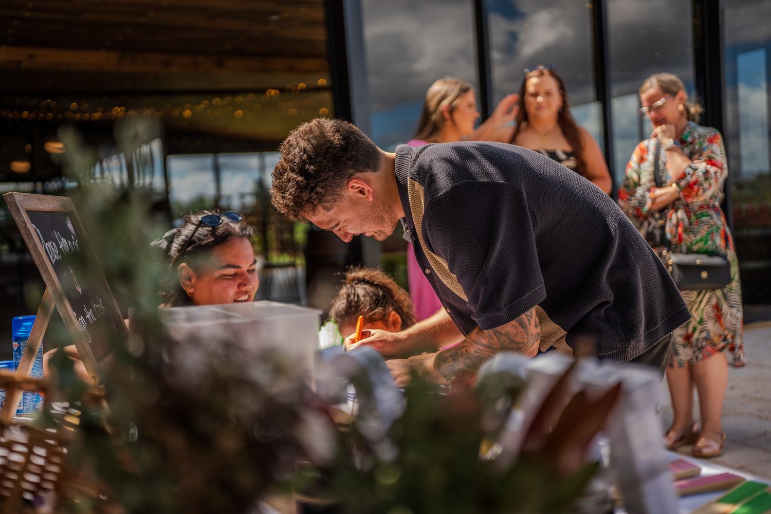 People gathered around a buffet table during an outdoor event with natural lighting.