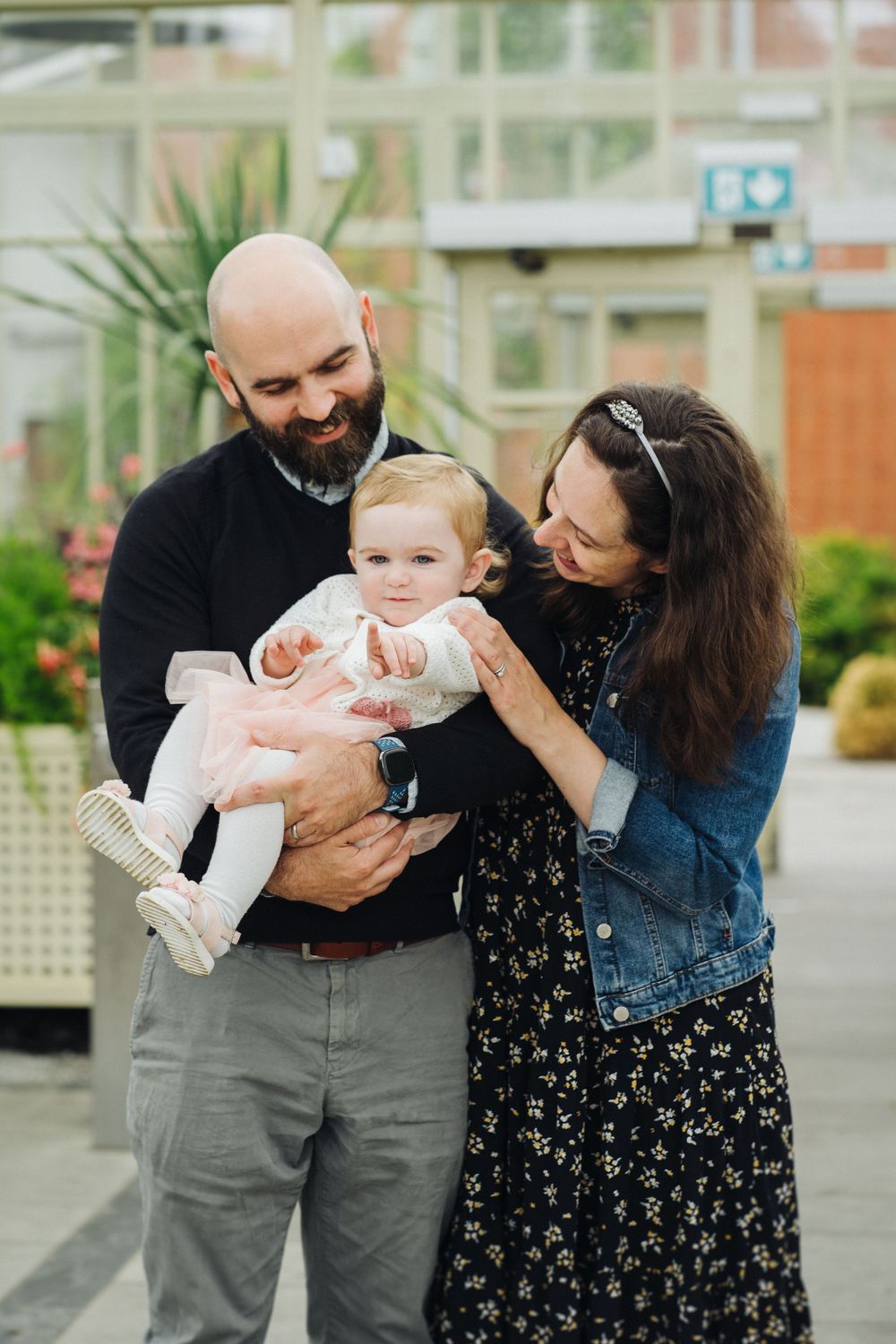 A couple in casual attire shares tender moments with their baby outdoors in a series of candid photos.