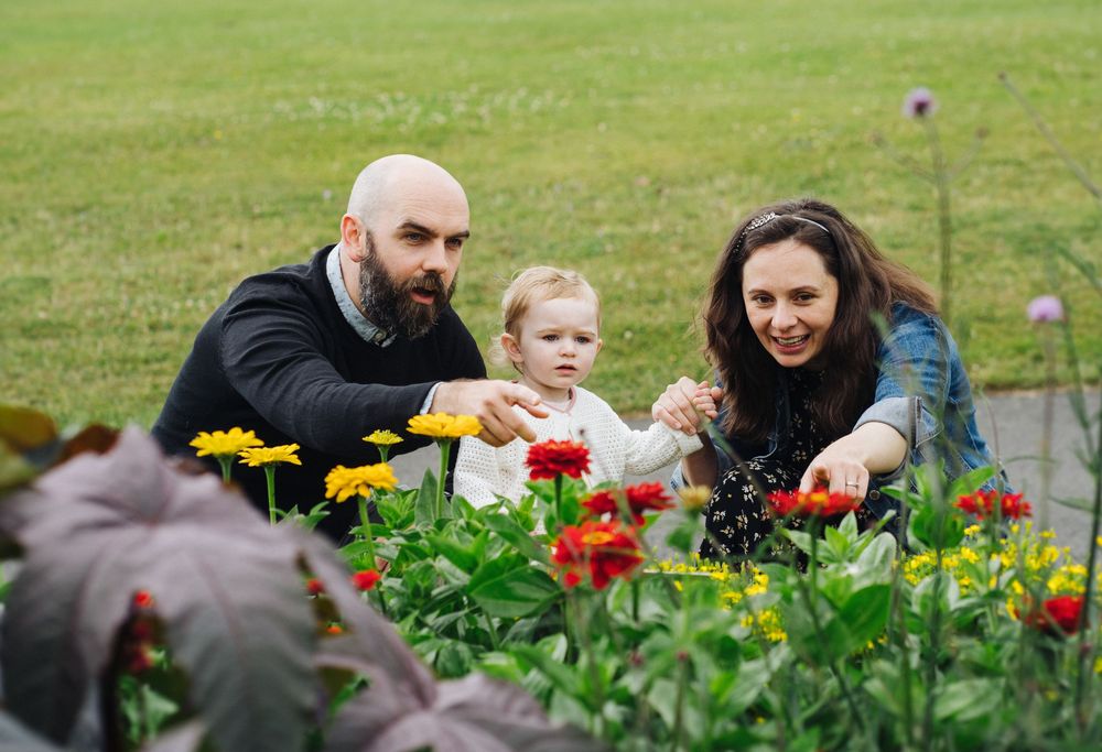 A family enjoys picking colorful tulips together at a flower farm on a sunny spring day.
