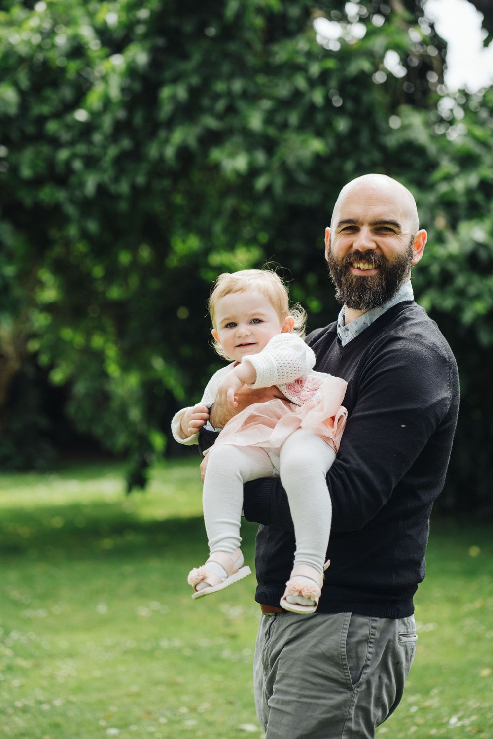 A tender moment between parent and baby playing together in a lush green garden setting.
