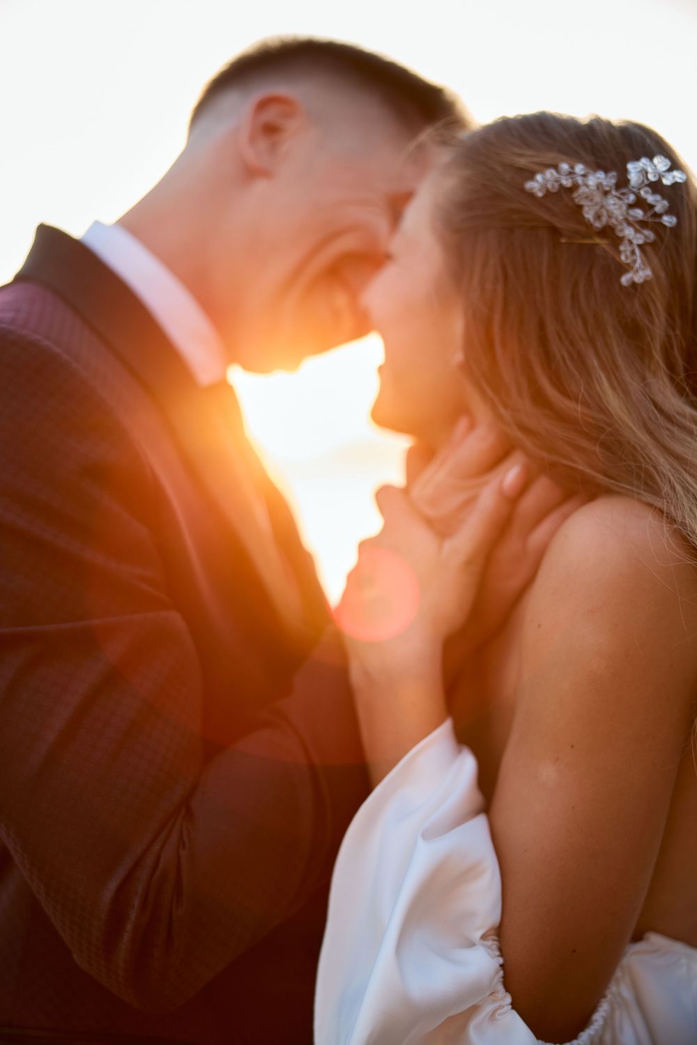 An intimate wedding portrait backlit by warm golden sunlight.