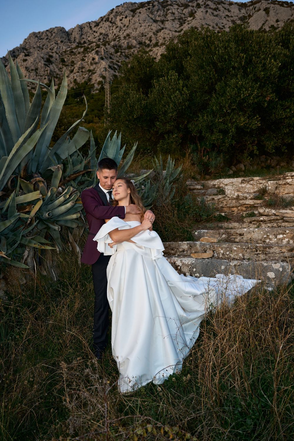 A romantic moment captured in an outdoor setting with agave plants and rocky terrain.