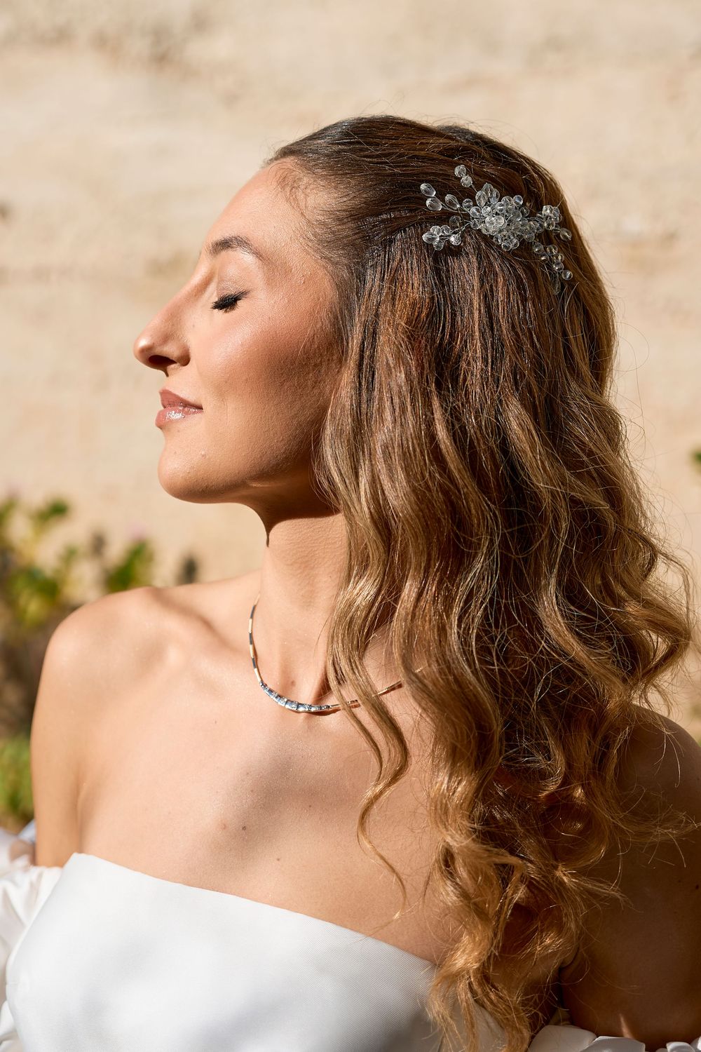 Profile views of a woman with wavy brown hair in a white top against a light background.