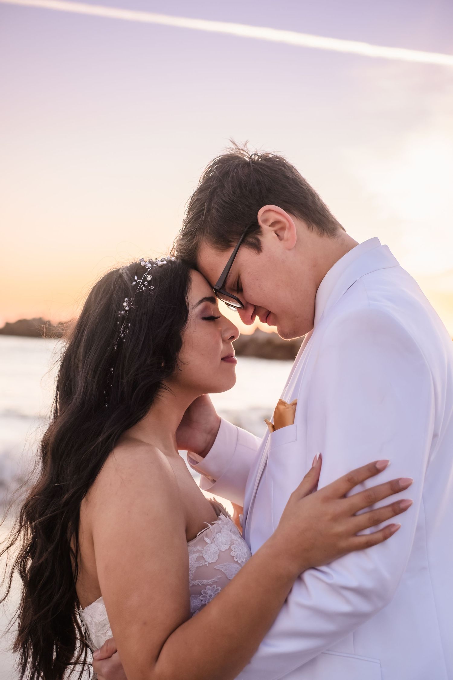 A romantic couple embraces on a beach at sunset in a series of intimate photos. At twin lakes beach state park in santa cruz california
