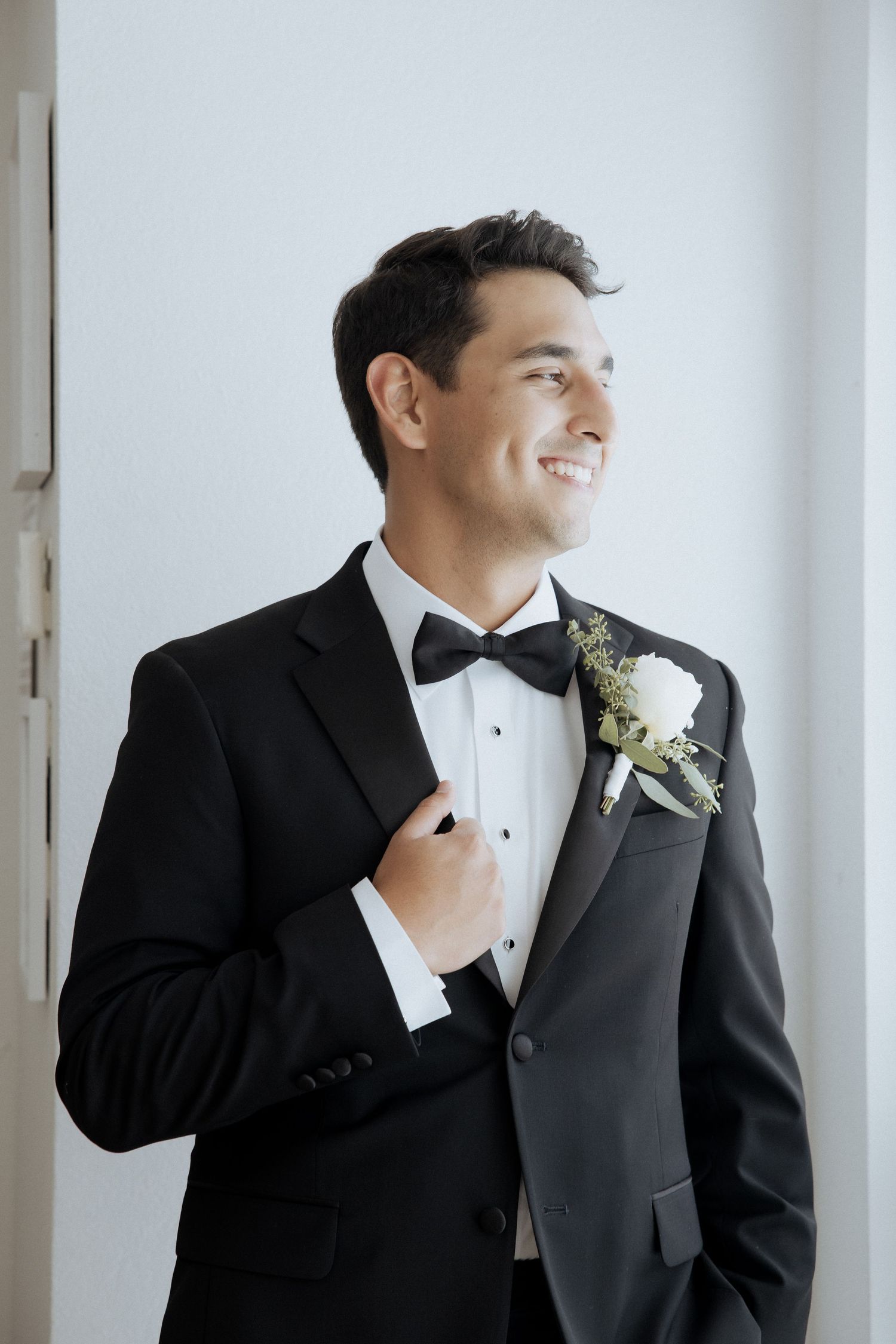Two men in gray suits share a candid laughing moment while getting ready for a formal event.
