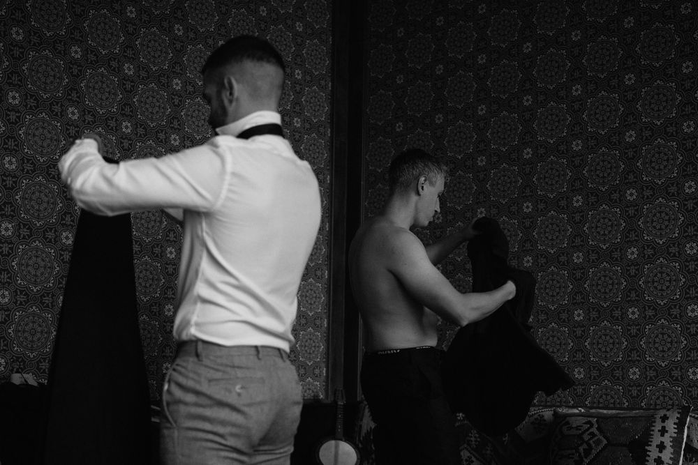 Two dancers practicing their moves against a dark patterned wallpaper in black and white.