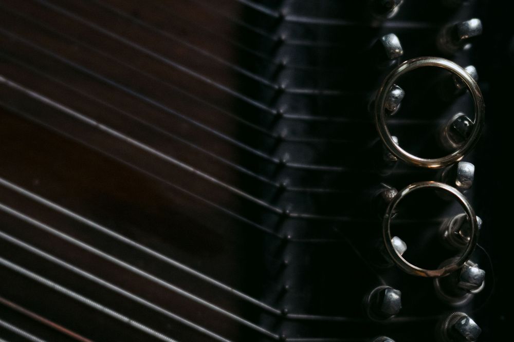 Detailed macro shot of piano strings and hammers inside a grand piano showing the mechanical components in low light.