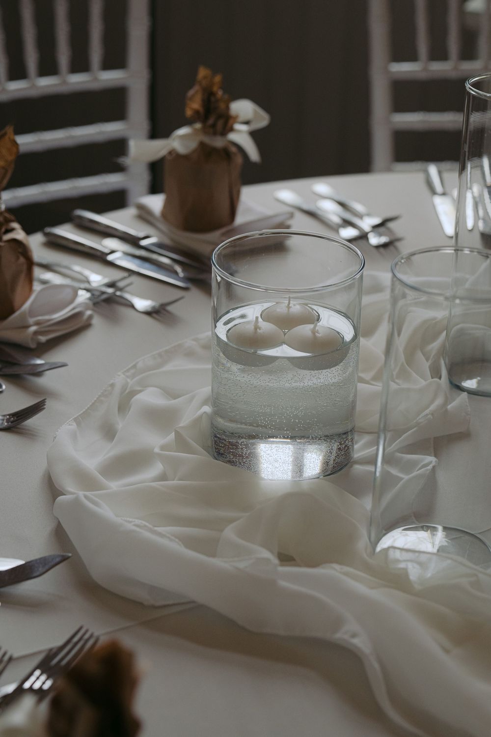 An elegant table setting with a glass of water, white linens, and silverware arranged for a formal dining experience.
