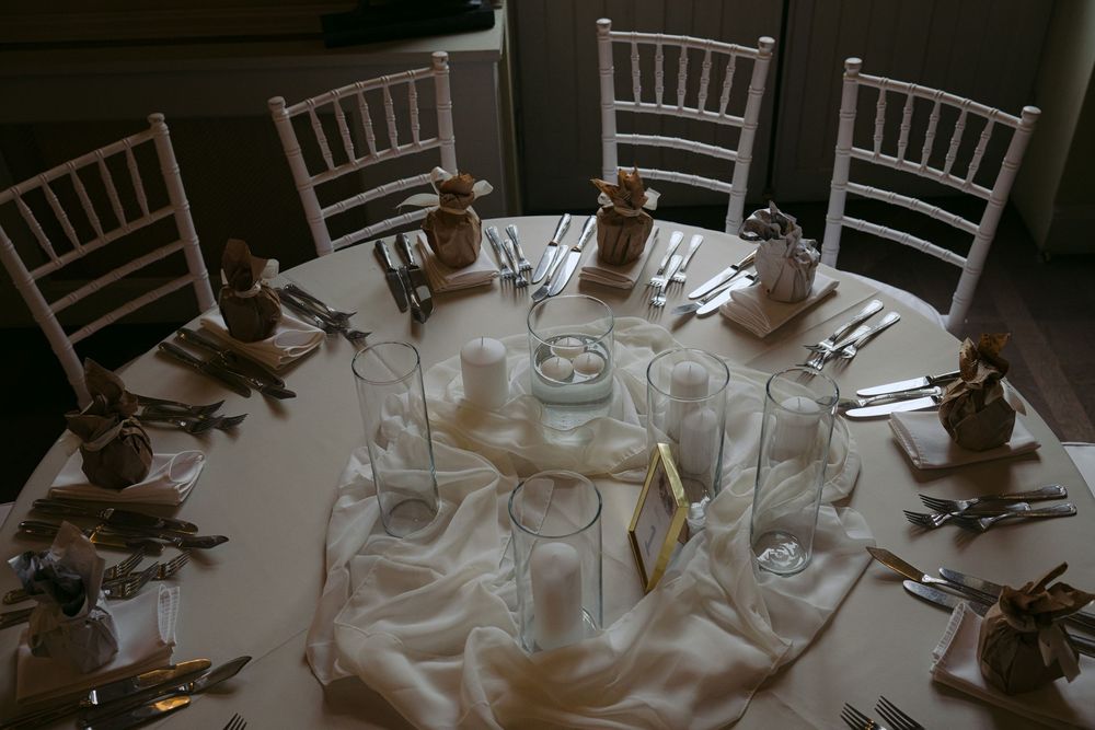 Elegant white chiavari chairs surround round tables set with formal place settings at a wedding reception.