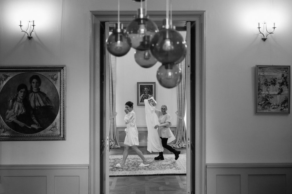 A black and white photograph shows a vintage party setting with balloons and wall decorations in an elegant room.