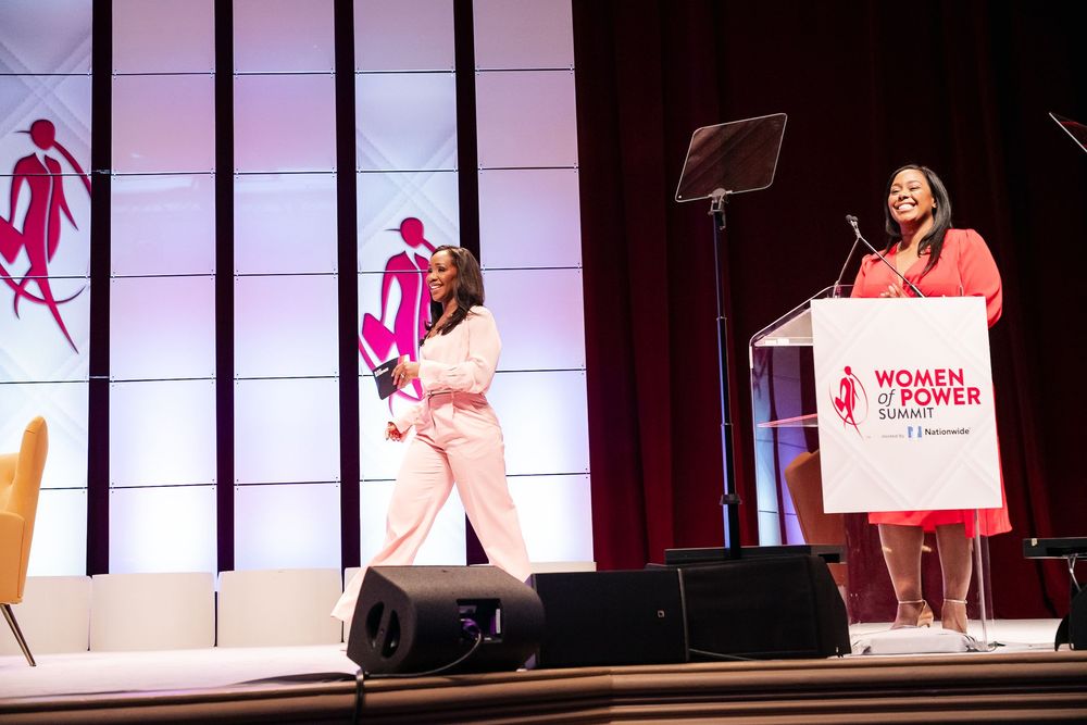 Professional conference stage setup with pink lighting and multiple podiums displaying Women's Forum branding.