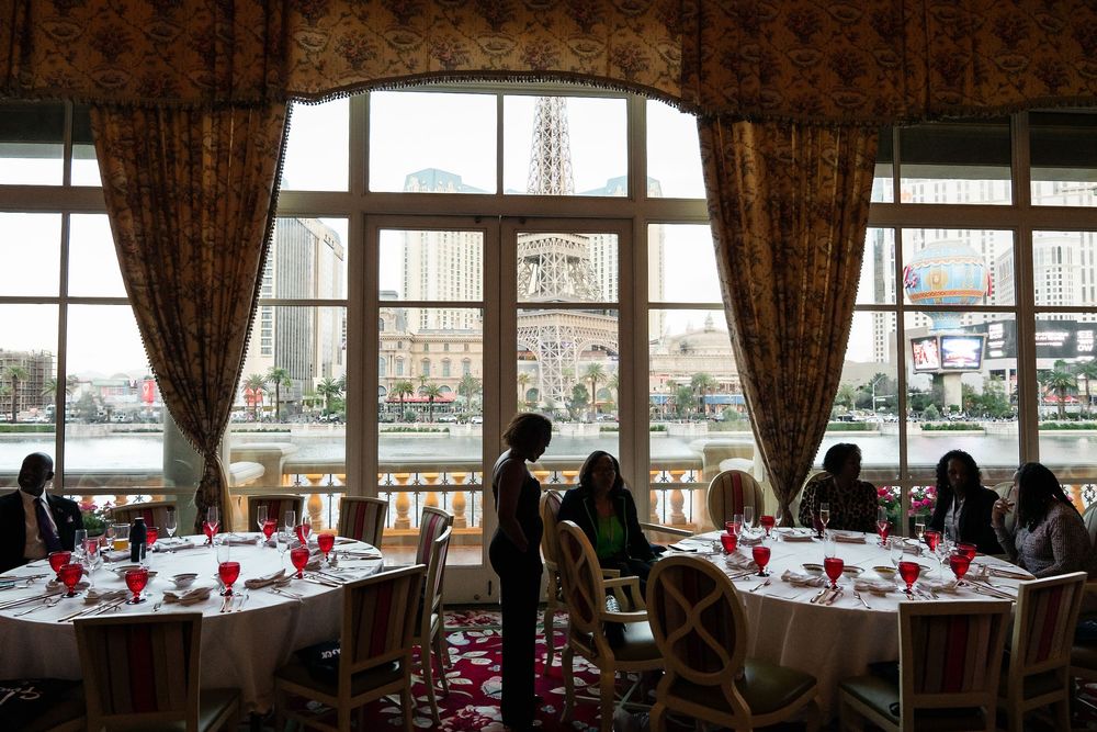 Elegant dining room with waterfront views through large windows, featuring round tables set for a formal event.