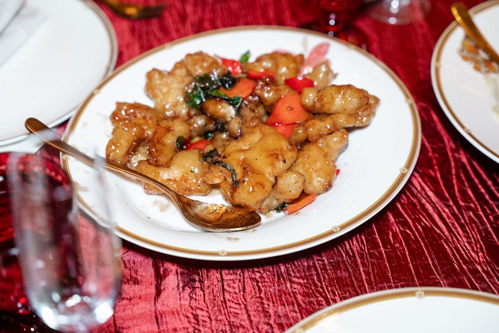 Chinese stir-fried chicken dish with vegetables served on white plates on a red tablecloth.