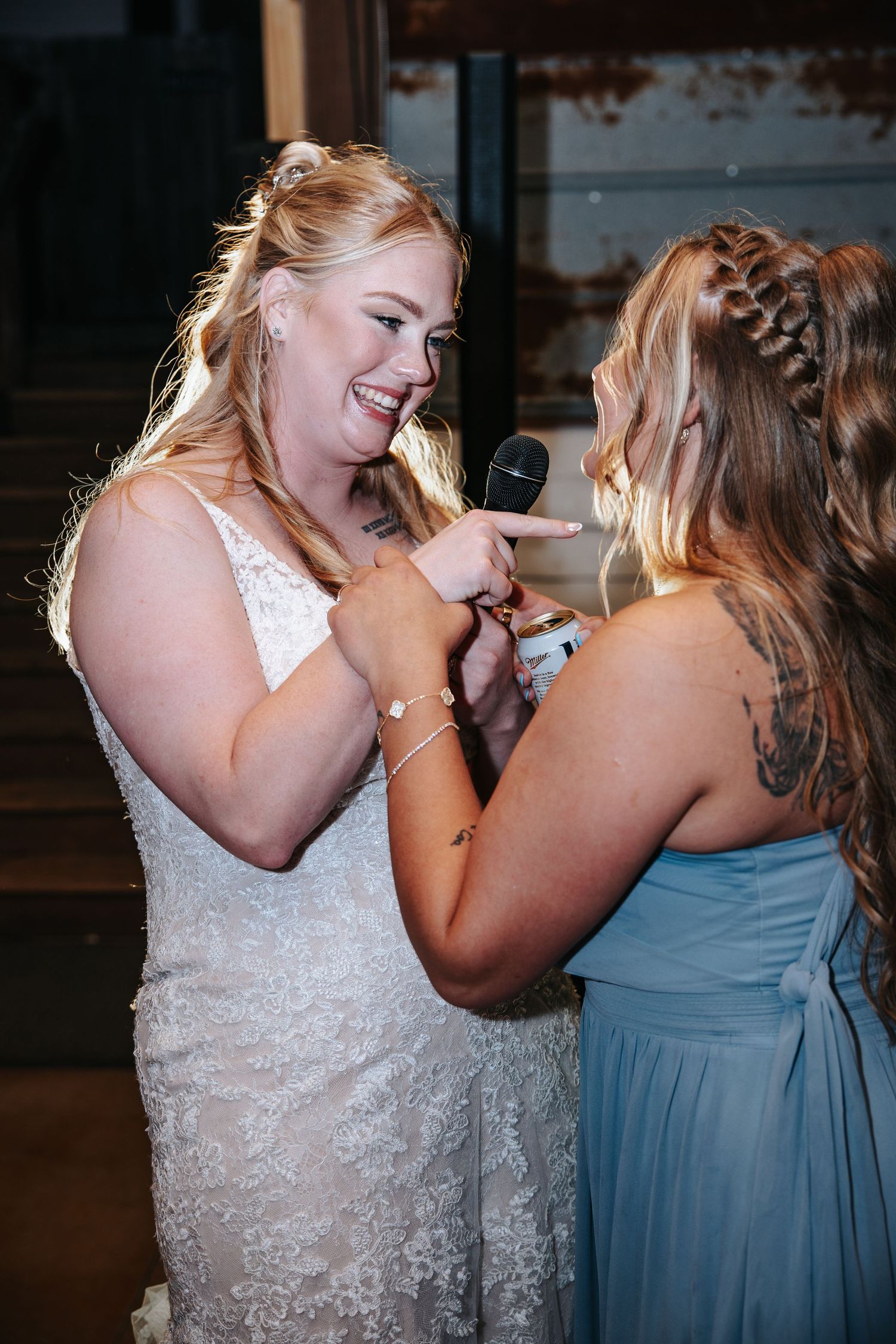 Two people in formal attire share a joyful moment laughing together at what appears to be a wedding reception.