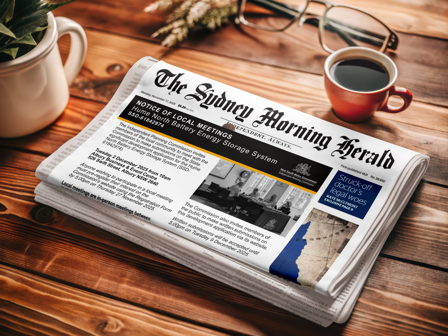 A newspaper titled 'The Sydney Morning Herald' sits on a wooden table next to a coffee cup and potted plant.