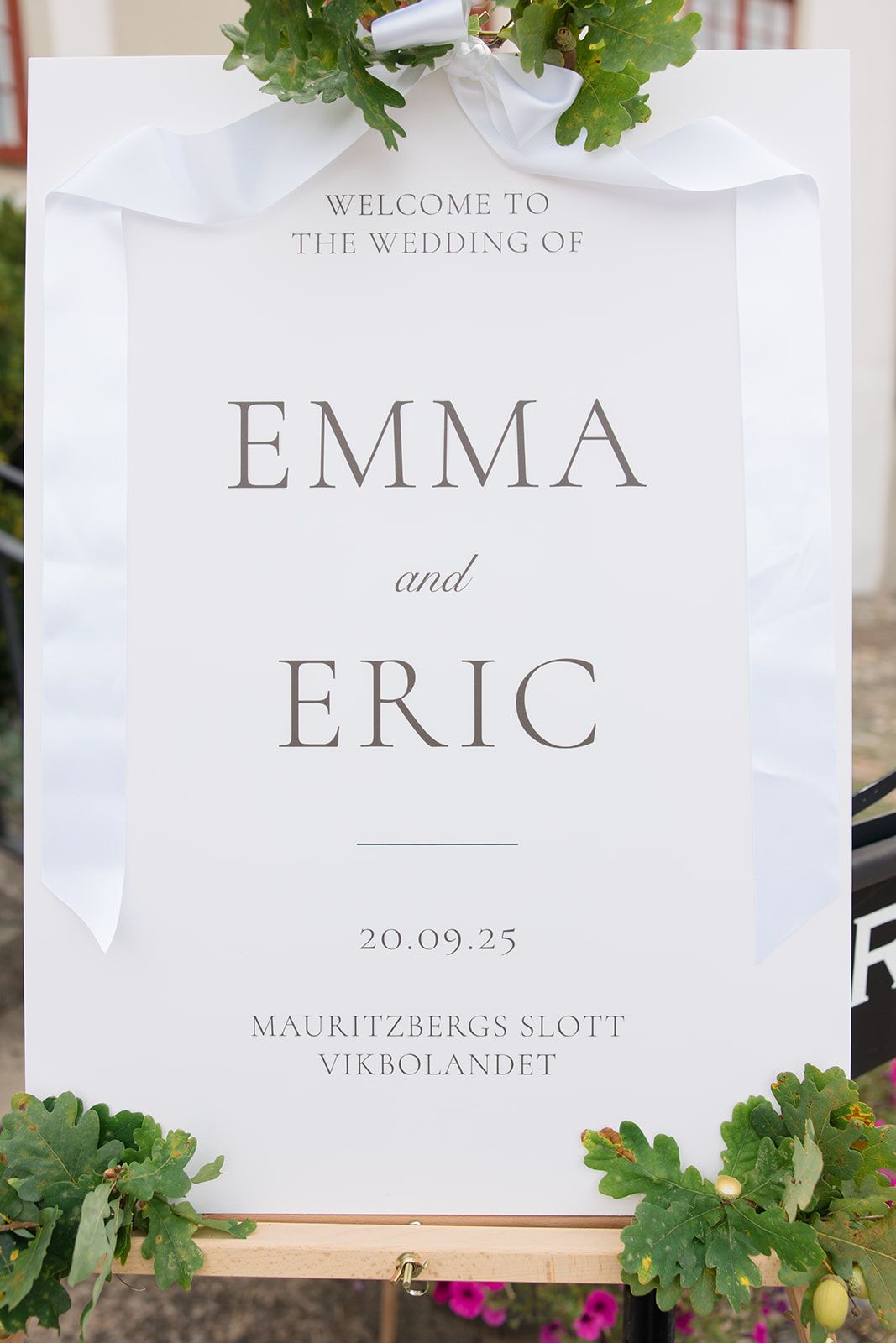 Elegant wedding welcome sign for Emma and Eric's ceremony at Mauritzbergs Slott featuring green foliage accents.