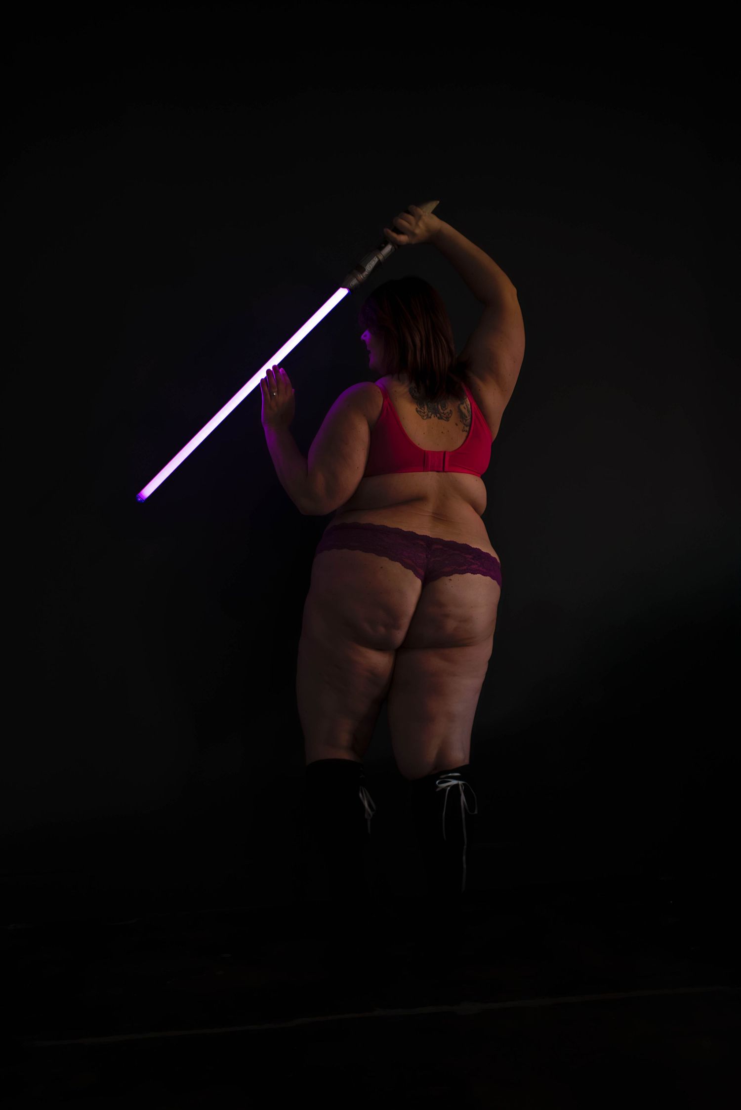 Boudoir photography of a plus size woman with a sword in a dark and moody studio in Salt Lake