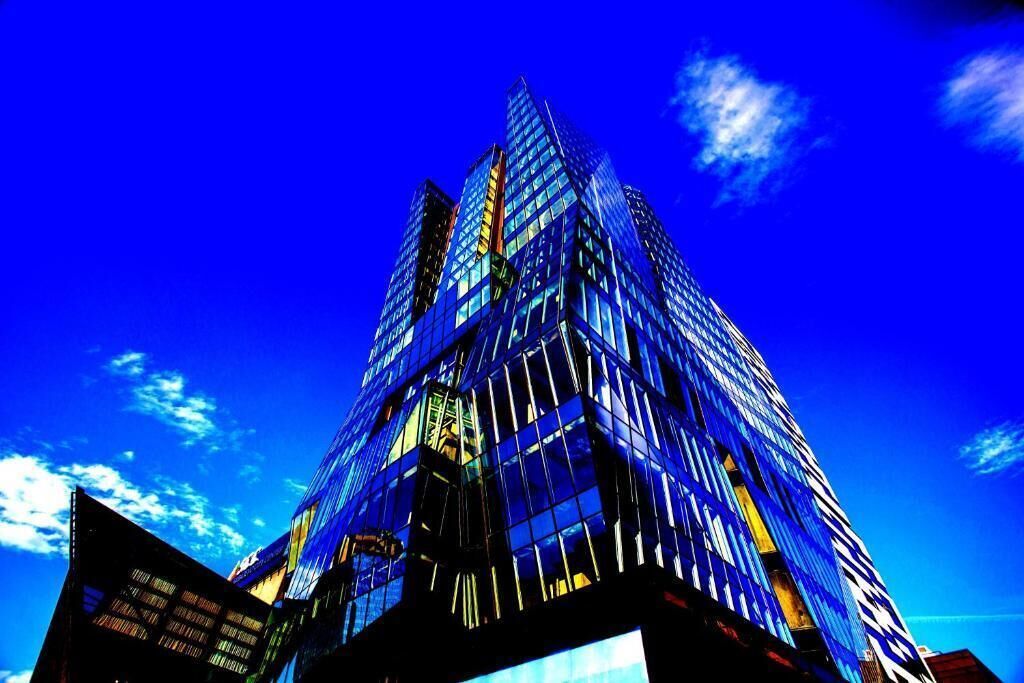 Modern skyscrapers with glass facades reflect bright blue sky and sunlight in an urban cityscape.