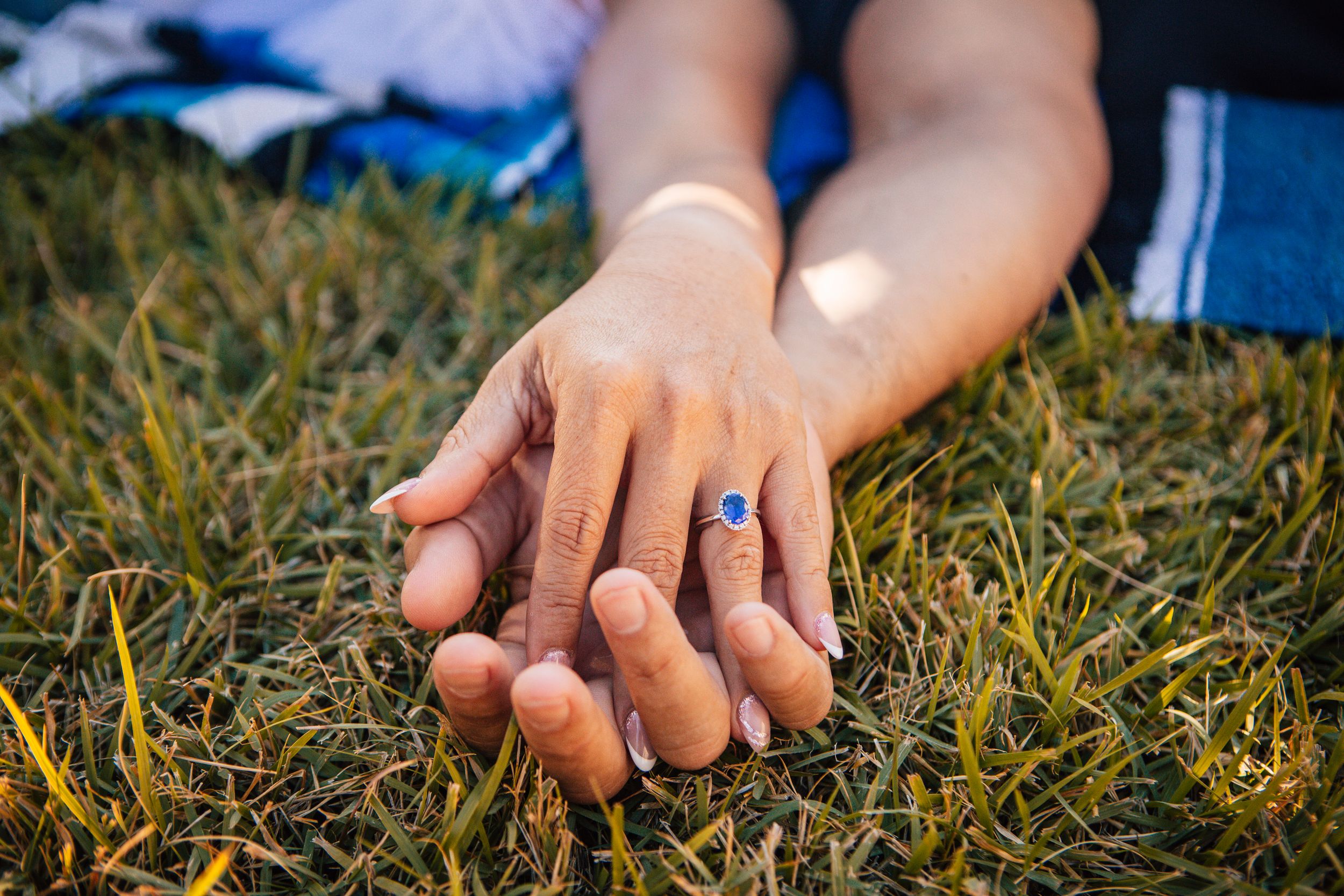 A close-up sequence of hands plucking blades of grass from a lawn in natural sunlight.