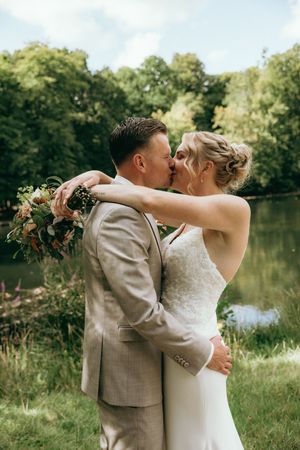 Romantic wedding portrait by a lake with couple in formal attire.