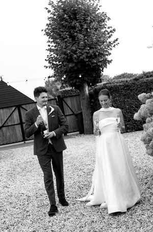 Black and white candid photo of a couple celebrating during their backyard wedding reception.