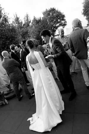 Black and white photo of wedding guests mingling during an outdoor reception celebration.