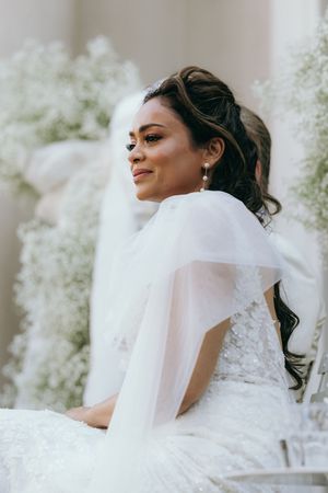 Close-up details of a white wedding veil and dress in soft natural lighting.