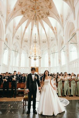 Elegant church wedding ceremony with ornate vaulted ceiling and chandeliers.