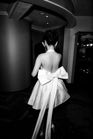 Dramatic black and white photo of bride's dress with flowing bow detail.