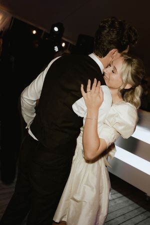Intimate dance moment captured in dramatic lighting at wedding reception.