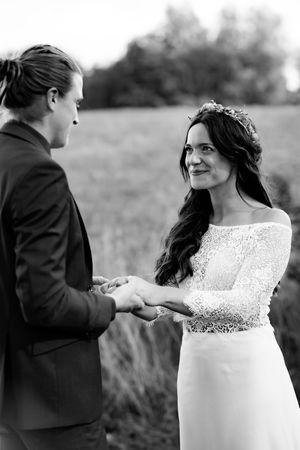 Black and white portrait of a couple holding hands during an intimate outdoor wedding moment.