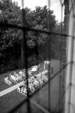 Black and white aerial view of an outdoor wedding setup with rows of white chairs.