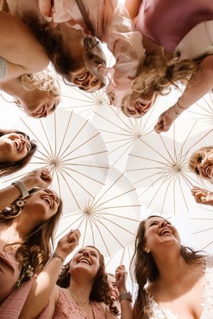 Group photo looking up through white parasols creating a joyful circular composition.