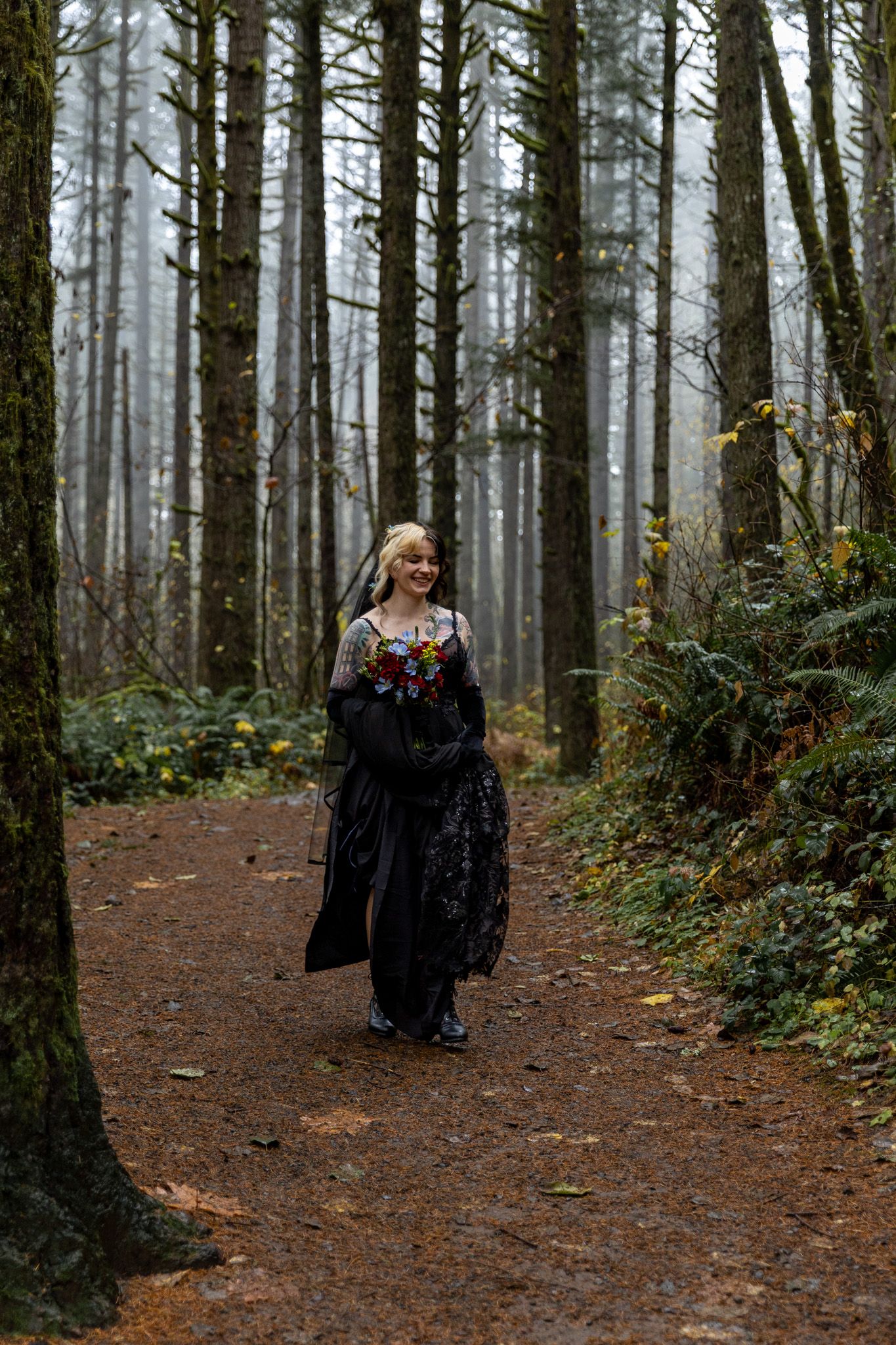 Bride walking in her black wedding dress through a foggy forest to her elopement in Washington State. PNW Elopement Photographer