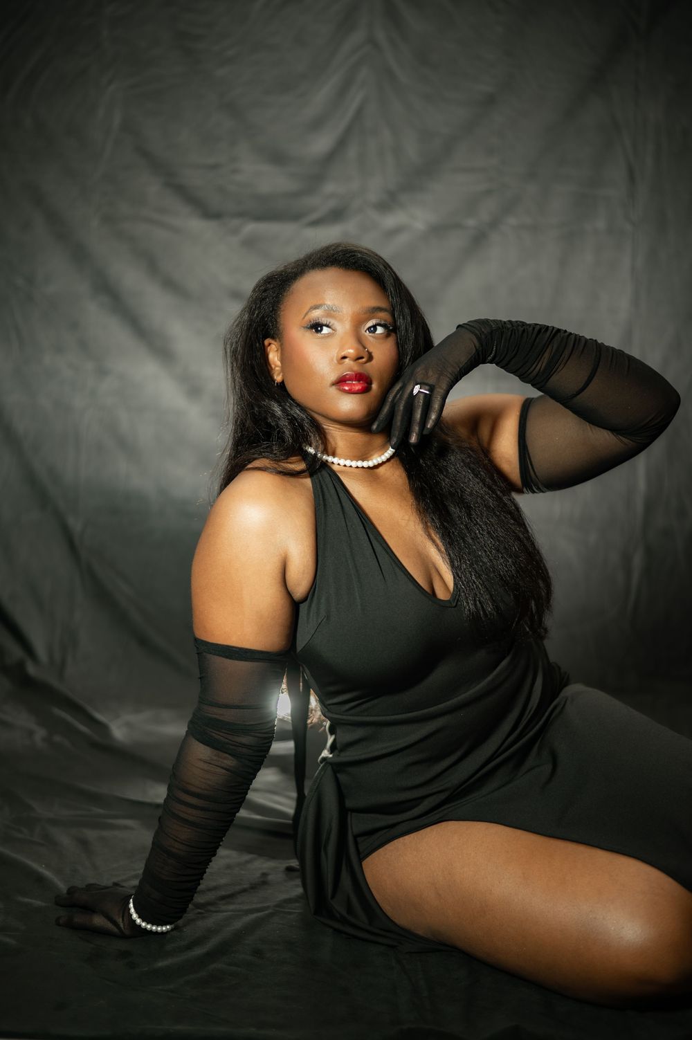 Glamour portrait series in black outfit with sheer sleeves against dark background showing artistic poses.