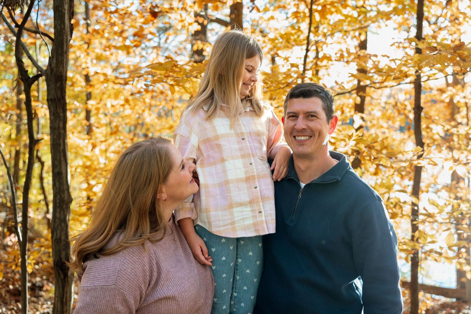 Family portrait of parents and daughter on wooded path — relaxed outdoor family photography