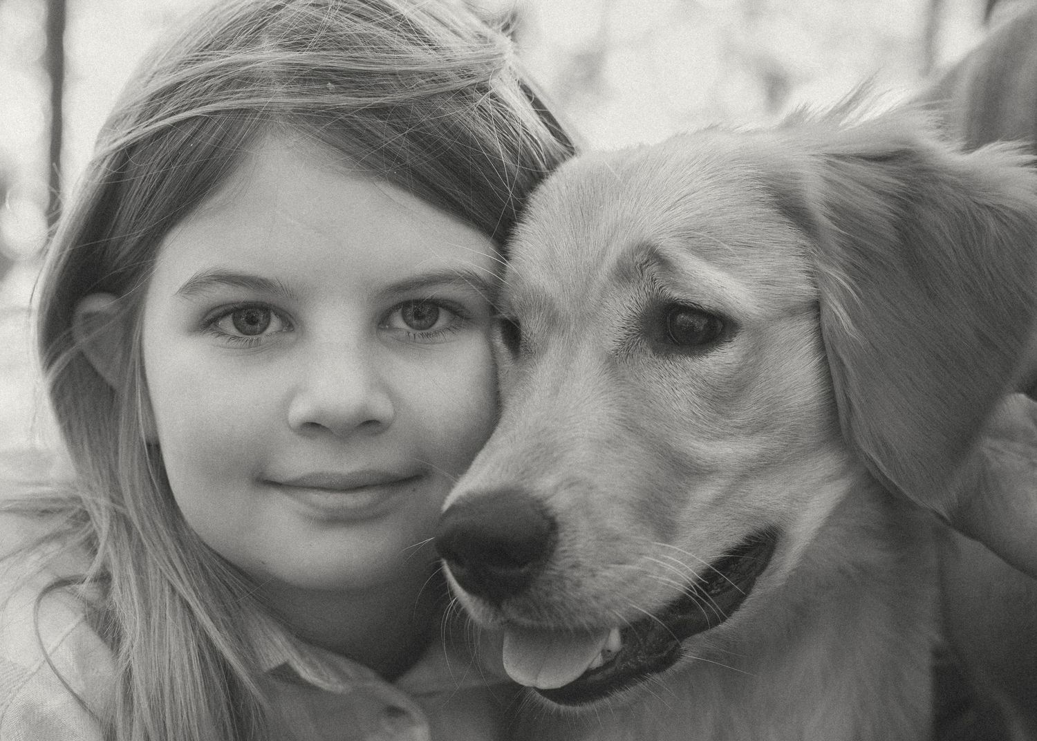 Black and white portrait of young girl cuddling her dog; natural light family photography
