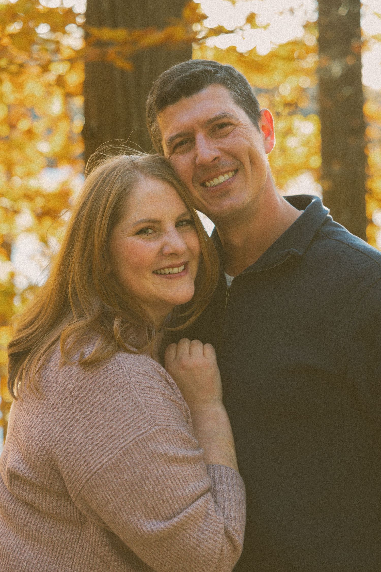 Smiling couple embracing in autumn woods — natural light family and couples photography