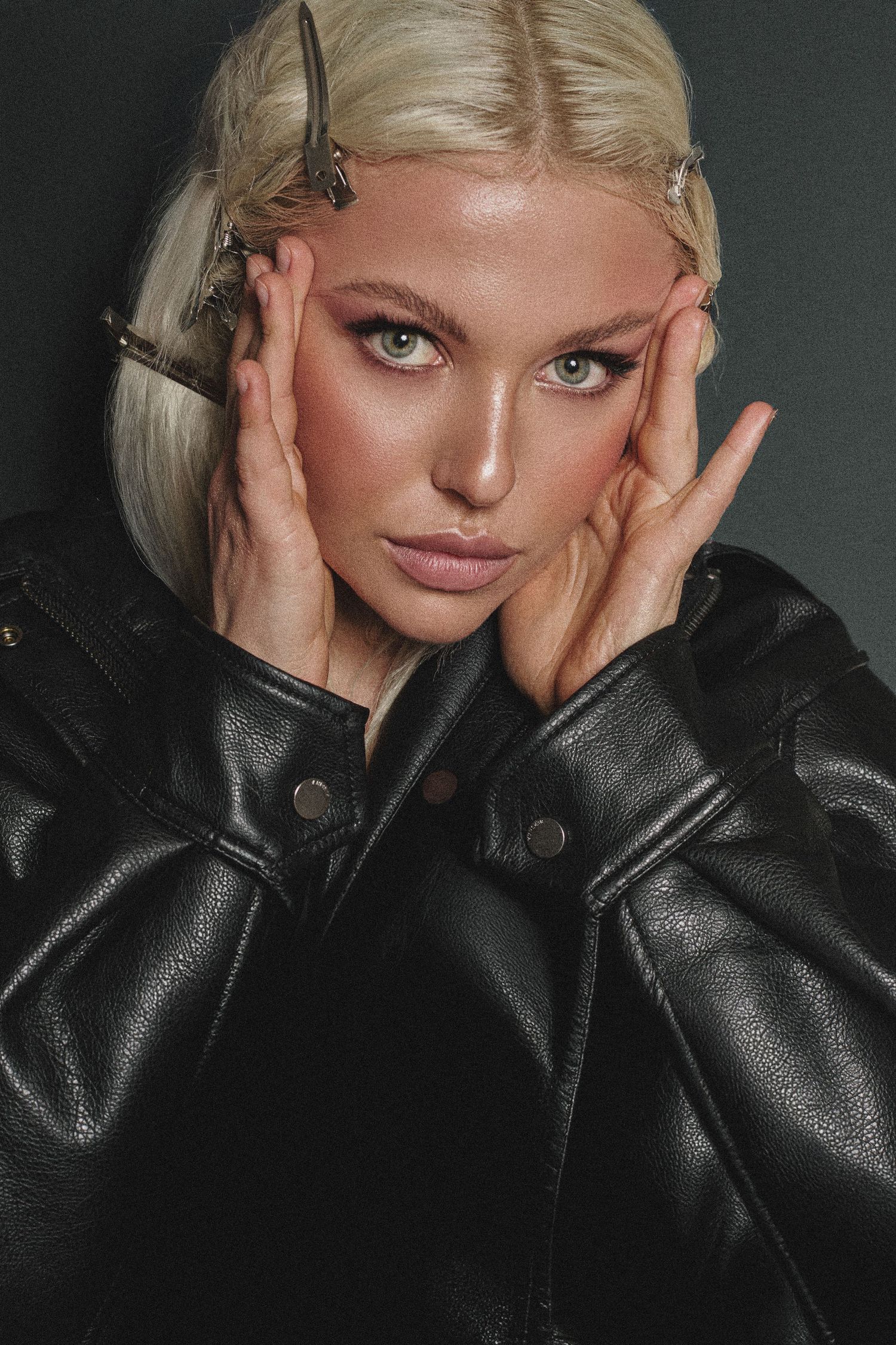 Studio fashion portraits in black leather jacket against dark background.