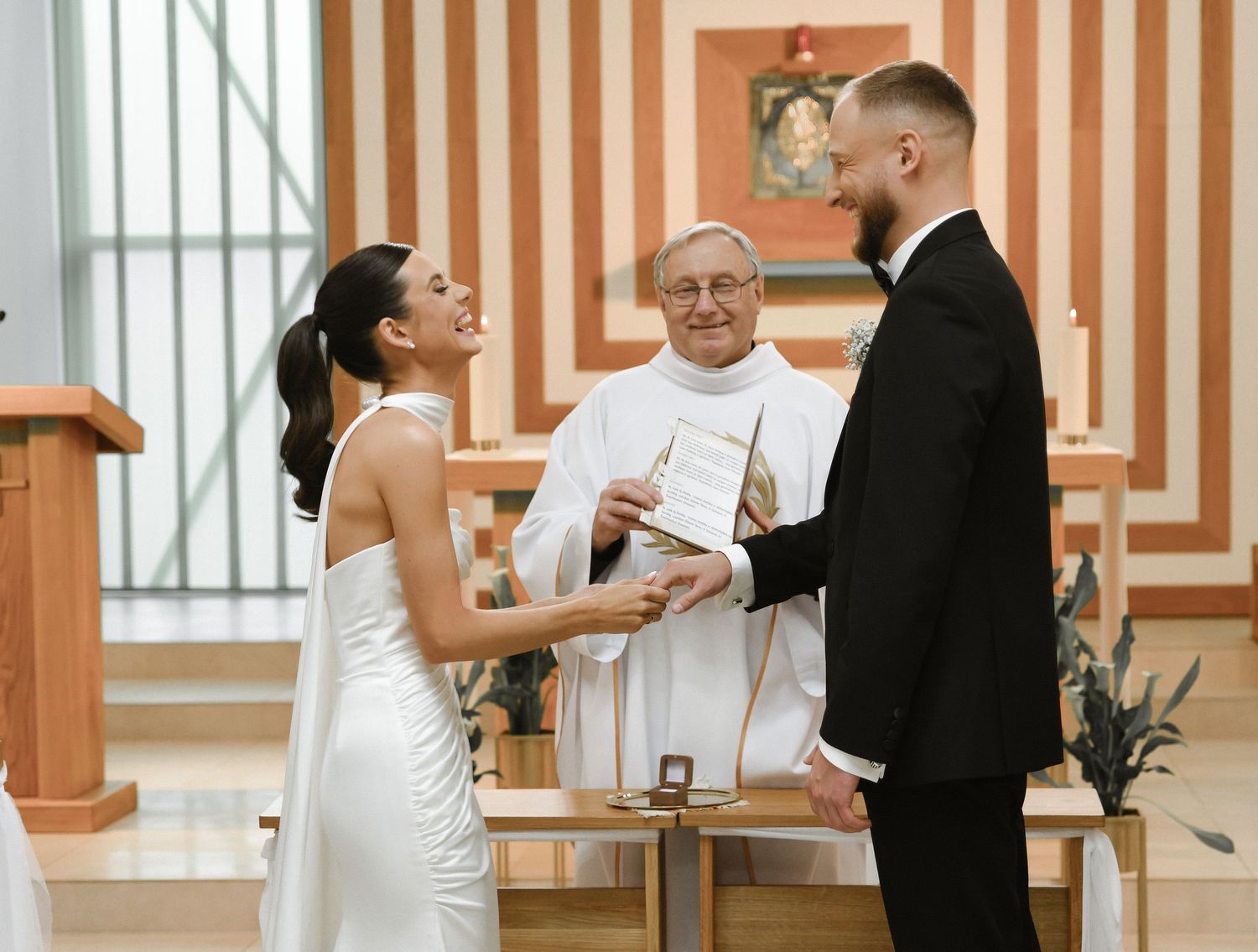 A bride in a white dress and groom in a black suit share a tender moment during their wedding ceremony.