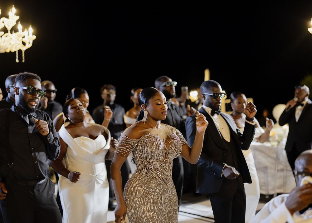 Wedding guests dance and celebrate together on a dimly lit dance floor at an evening reception.