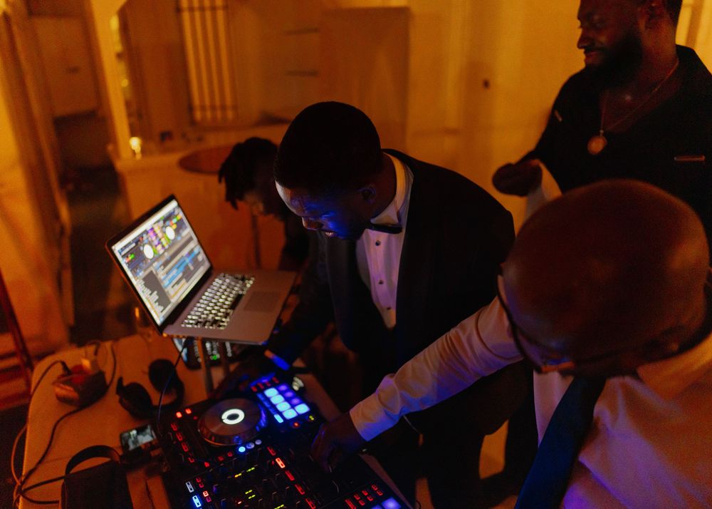 A group of DJs performing at a dimly lit nightclub with electronic equipment and turntables.