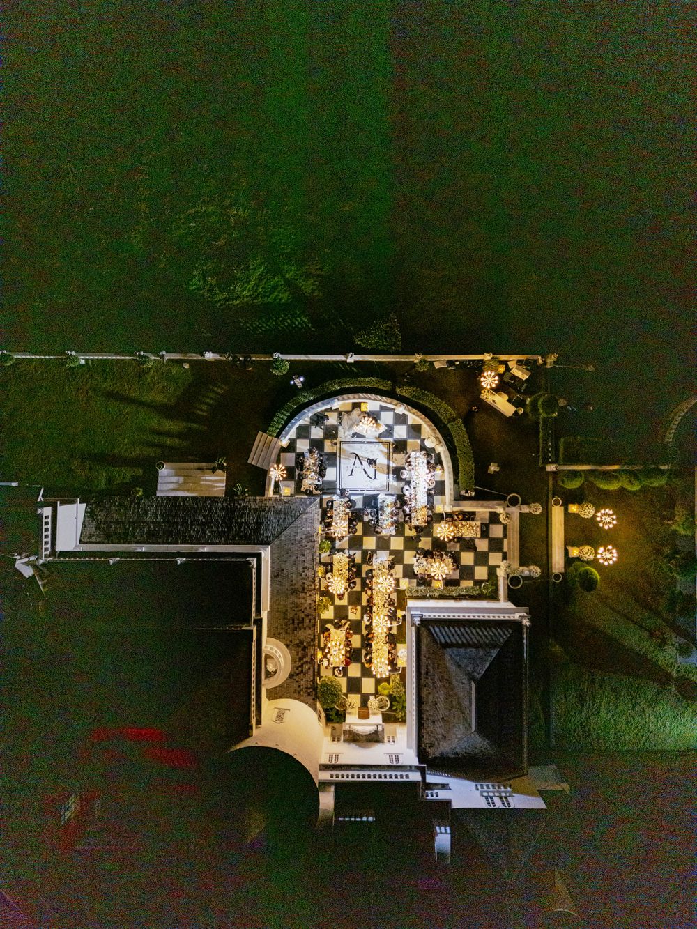 Birds-eye view of illuminated checkered patterns and architectural structures at night.