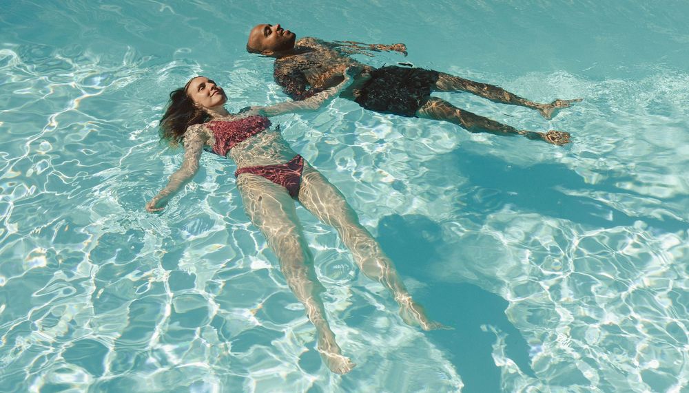 People floating and relaxing in crystal clear turquoise pool water.